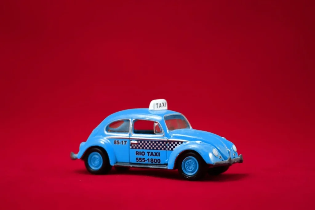 A blue taxi on a flat red surface with a red background.