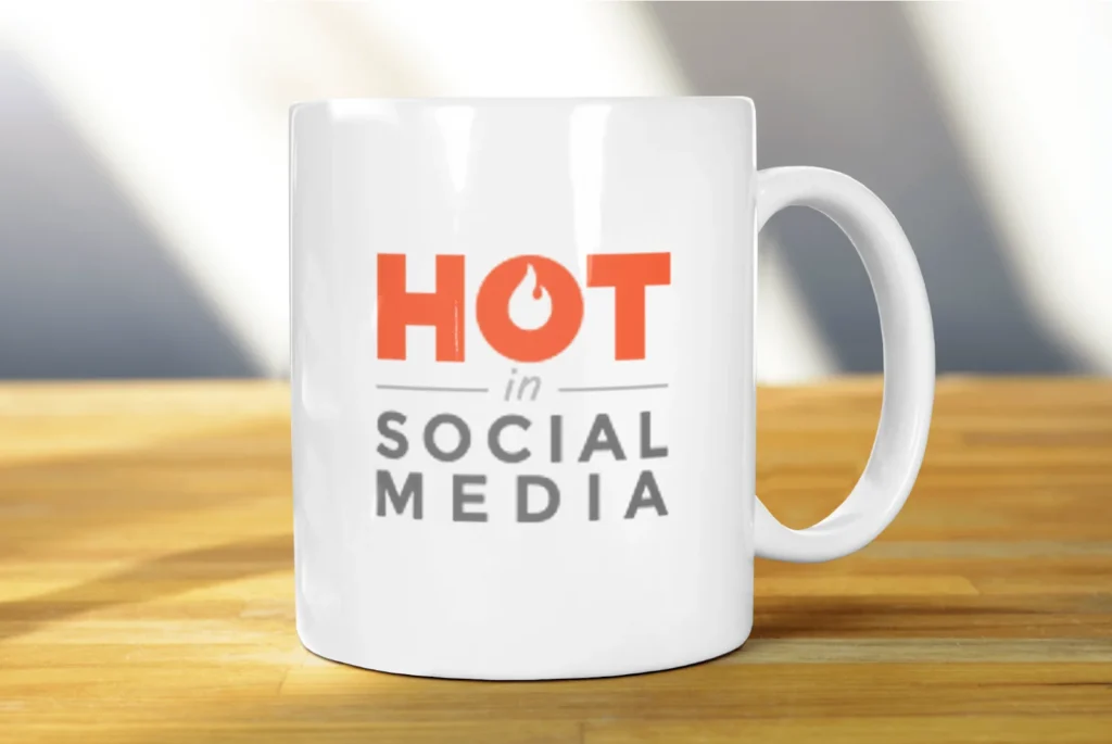 The Hot in Social Media logo on a white mug sitting on a wooden table