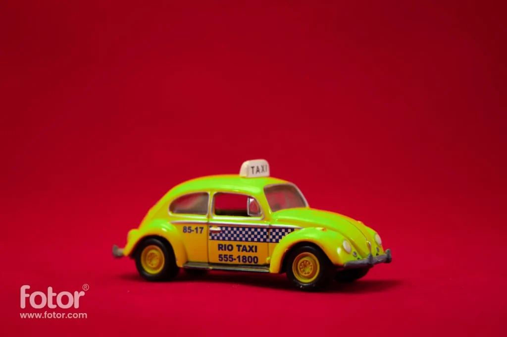 A green and yellow taxi on a flat red surface with a red background.